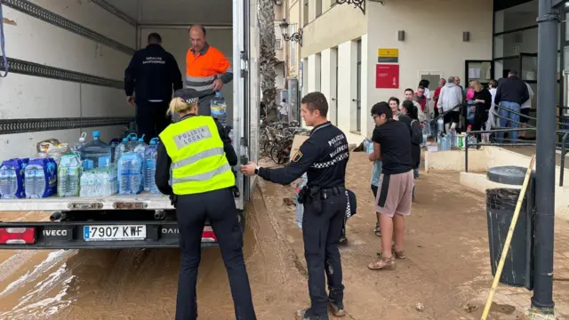 Council workers hand out water to queuing residents in Valencia