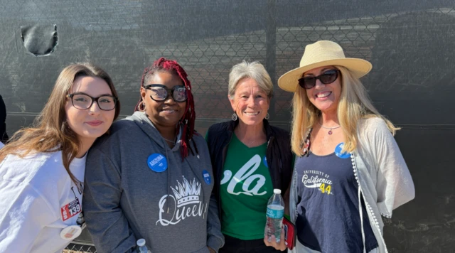 Four women backing Harris pose for photo. From left to right: brunette with black glasses and white shirt, Black woman with red hair and grey hoodie, short, grey haired woman with black jacket. Next to her his long-haired blonde with blue tank top