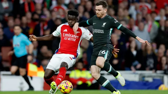 Arsenal's Bukayo Saka and Liverpool's Andy Robertson run for the ball