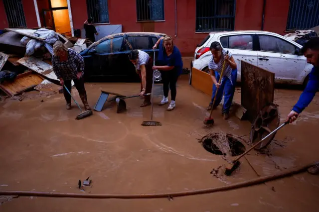 People clean mud from the streets, following floods, in La Torre neighbourhood in Sedavi, Valencia, Spain, October 31