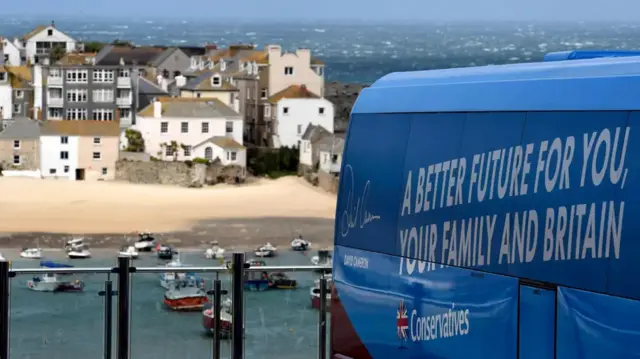 A Conservative Party bus parked in front of a beach in Cornwall