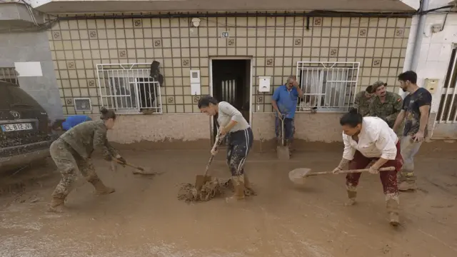 Residents clean the mud covering a flooded street in Riba-Roja, Valencia, 01 November 2024