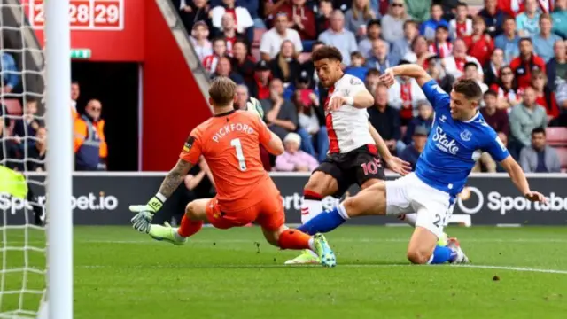 Che Adams of Southampton shoots wide while under pressure from Jordan Pickford and James Tarkowski