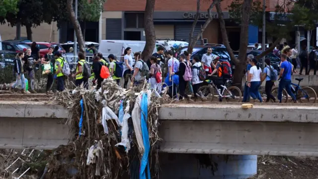 A group of volunteers, some in high vis, others in plain clothes, walking across a bridge, some holding cleaning supplies