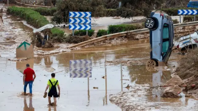 People walk in a mud-covered road in the flood-hit city of Picanya yesterday