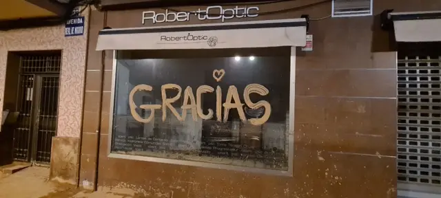 A shop window in La Torre with Gracias written on it in mud