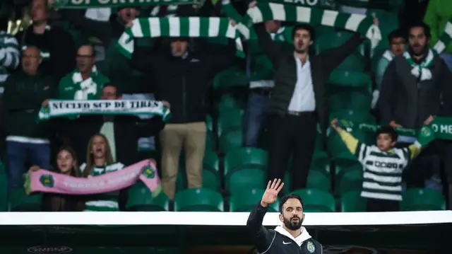 Sporting fans hold scarves aloft behind Ruben Amorim as the Sporting coach stands with his hand raised