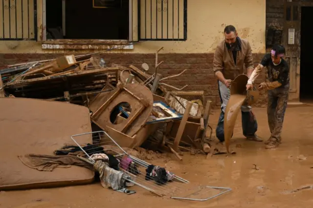 People clear mud and possessions from their homes after the recent flash flooding in the nearby municipality Alfafar