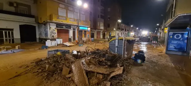 A picture of flooding damage in the La Torre area of Valencia in Spain. There is a big pile of rubble in the centre of the picture and mud covers the streets