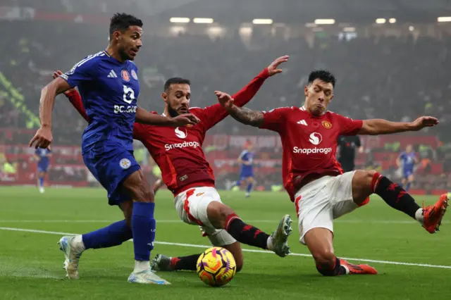 James Justin is challenged by two Man Utd defenders