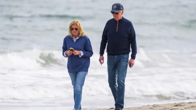 U.S. President Joe Biden gestures as he and first lady Jill Biden walk on the seashore in Rehoboth Beach, Delaware