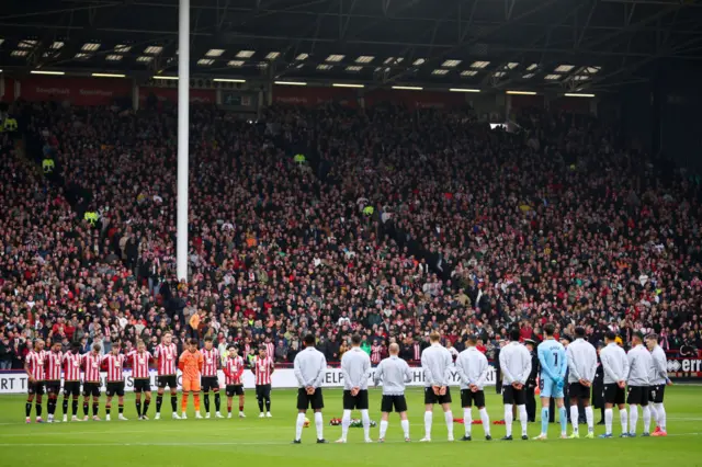 Players, match officials and fans take part in a minute's silence