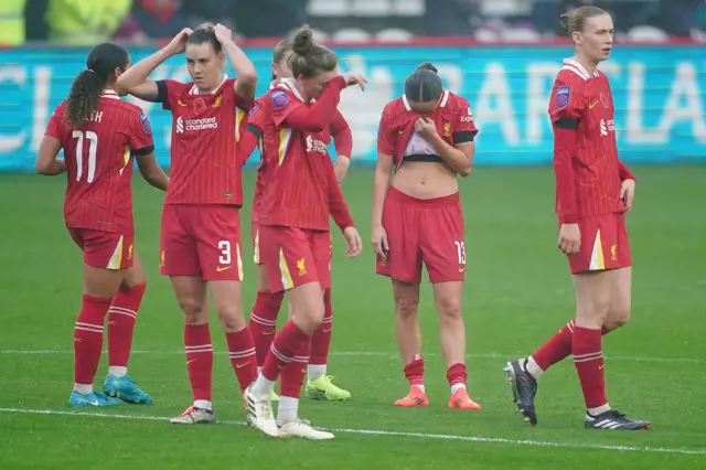 Liverpool players look dejected as they stand on the pitch at full time