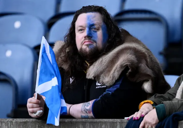 A fan of Scotland, holding a miniature national flag and wearing Braveheart themed face paint, looks on as he enjoys the pre match atmosphere prior to the Autumn Nations Series 2024 match between Scotland and South Africa at the Scottish Gas Murrayfield