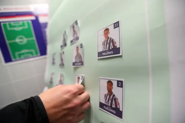 a member of West Bromwich Albion coaching staff pins todays starting players to a board inside the away dressing room