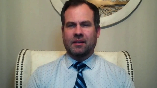 Warren Petersen in a blue shirt and tie, gazing at the camera