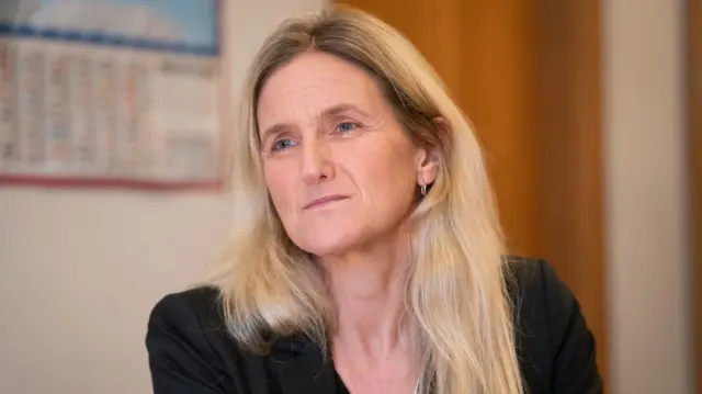 Kim Leadbeater, wearing a black jacket and with her long blonde hair loose, listens as she is interviewed in her parliamentary office.