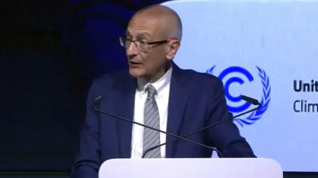 John Podesta speaking into two microphones at a podium