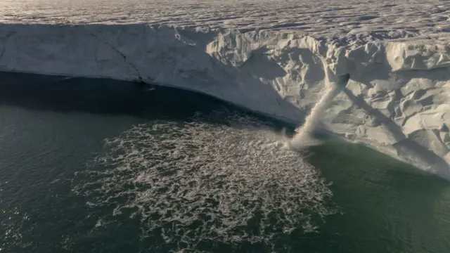 Iceberg with water flowing off the surface into ocean