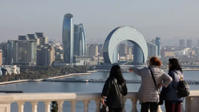 Visitors look towards the Crescent Bay skyscraper, center, and Caspian Sea waterfront in Baku, Azerbaijan, on Sunday, Nov. 10, 2024. T
