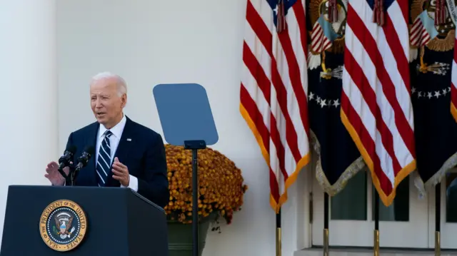 President Biden stands at a lectern in front of US flags