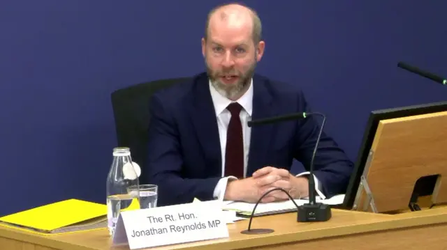 Jonathan Reynolds sitting in the inquiry with his hands on the desk in front of him