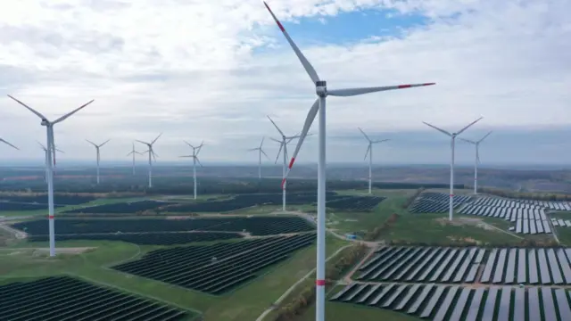 In this aerial view, electricity-producing wind turbines spin at a solar farm on November 1, 2022 near Klettwitz, Germany.