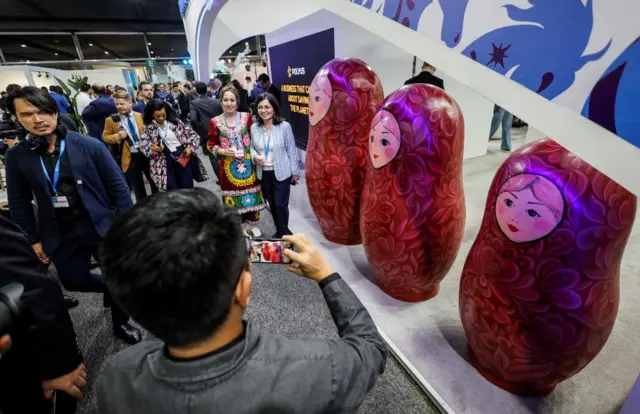 People standing next to three giant Matryoashka dolls taking a picture with them