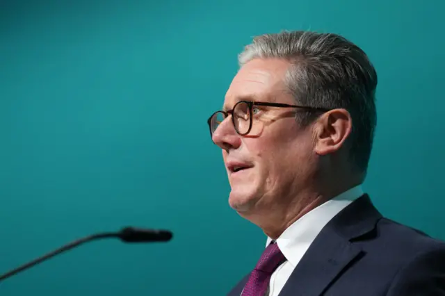 Starmer speaking into a microphone from a side on view of his shoulders and head