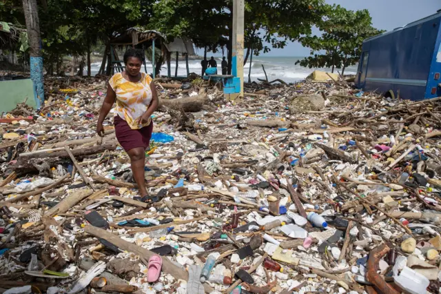 A woman walks along the beach of Manresa, covered with garbage after the passage of Hurricane Beryl, in Santo Domingo, Dominican Republic, 3 July 2024