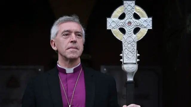 Archbishop of Wales, Andrew John poses with 'The Cross of Wales' which is a large silver cross he is holding in his hand