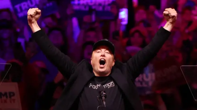 Elon Musk gestures to the audience during a rally