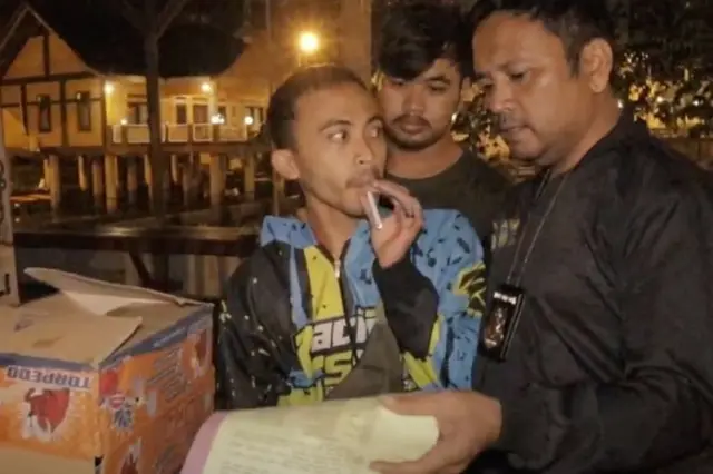 Asep Yadi Nurul Hikmah being arrested, while smoking a cigarette