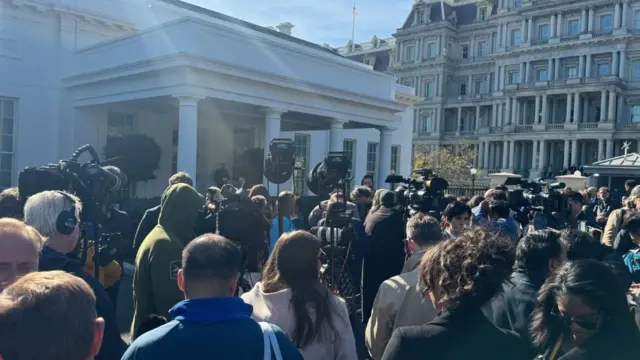 Reporters wait outside and crowd the steps where Donald Trump is expected to exit from the White House