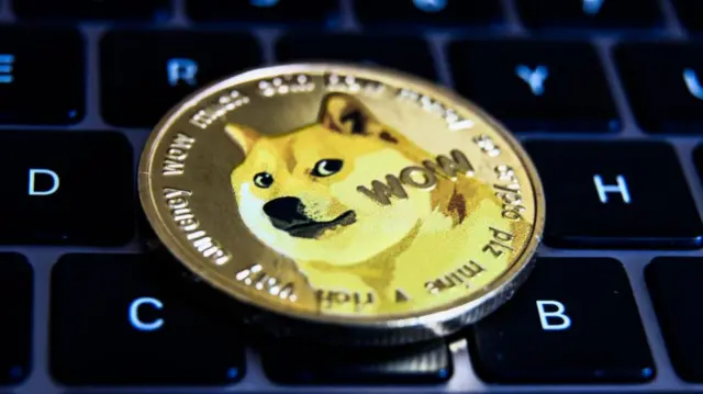 A Dogecoin token with a laptop keyboard in the background