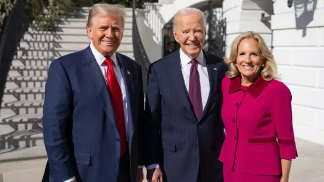 Two men in blue suits and woman in magenta suit smile