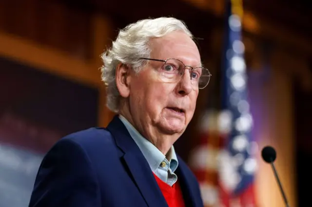 US Senate Republican Leader Mitch McConnell wearing a navy suit and red jumper at the US Capitol