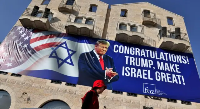 A man walks past a large billboard congratulating US President-elect Donald Trump, on the facade of Friends of Zion Museum in Jerusalem, 07 November 2024.