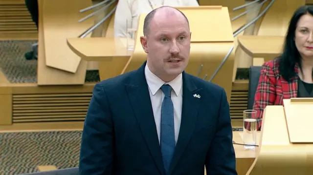 Health Secretary Neil Gray standing in the chamber speaking