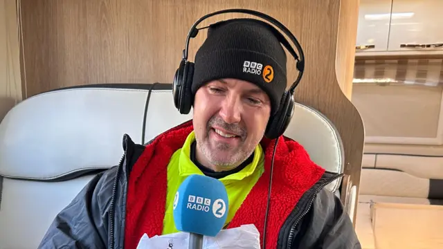 Paddy McGuinness crying in a caravan holding a Radio 2 mic