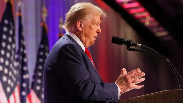 Trump gestures as he speaks into a microphone