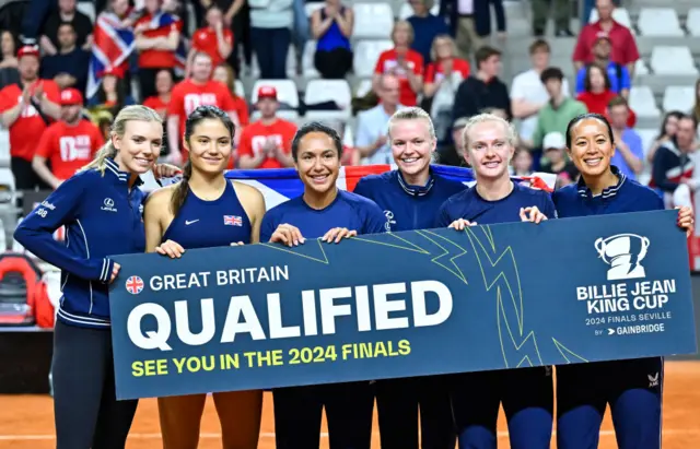 Katie Boulter, Emma Raducanu, Heather Watson, Harriet Dart, Franceska Jones and Captain Anne Keothavong of Great Britain hold a banner reading 'Qualified'