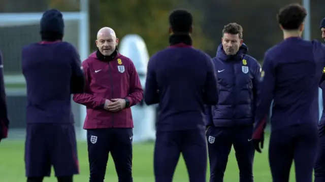 Lee Carsley, Interim Head Coach of England, talks to players during a training session.