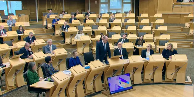 Chamber at Holyrood with Neil Gray standing speaking