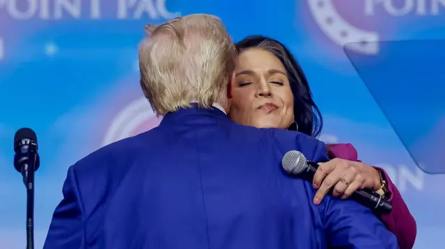 Former US President and Republican presidential nominee Donald Trump (L) embraces former Hawaii US representative Tulsi Gabbard (R) at the Turning Point PAC campaign rally at the Gas South Arena, in Duluth, Georgia