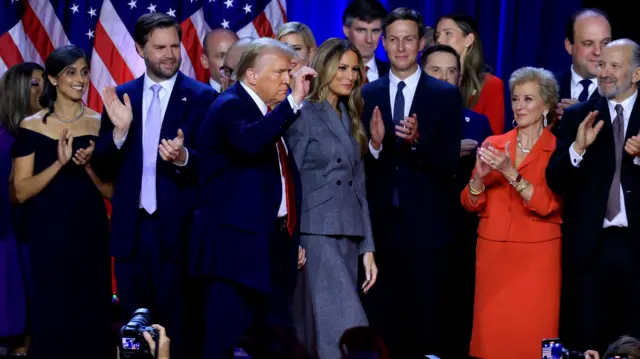 Trump on stage after winning the election, surrounded by his family and closest allies