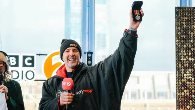 A jubilant Paddy holding up his grandfather's medal