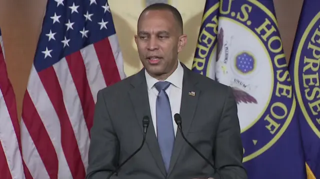 Hakeem Jeffries standing in front of the US flag