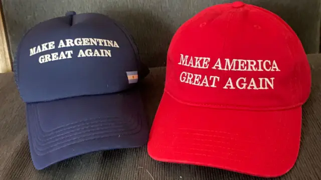 Two MAGA hats. On the left, a navy cap saying 'Make Argentina Great Again' and on the right a red cap saying 'Make America Great Again'