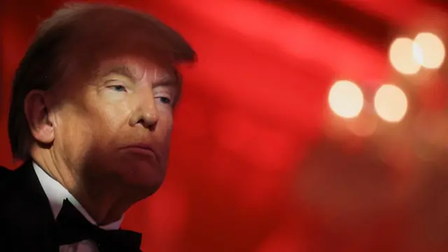 Trump wears a bowtie and suit as he looks out against a red background